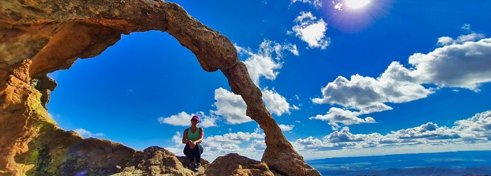 Turistas se deslumbran por un arco de piedra en las Altas Cumbres